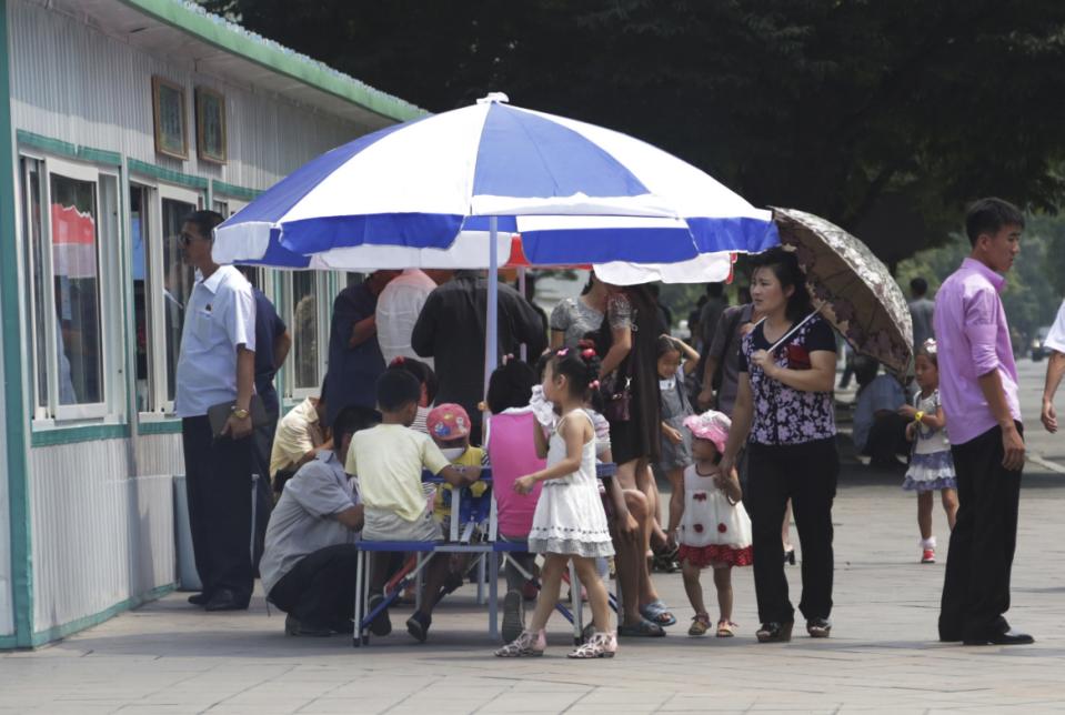 In this Aug. 16, 2015 photo, people queue up and have their meals at a food kiosk in Pyongyang, North Korea. Street stalls that offer North Koreans a place to spend - or make - money on everything from snow cones to DVDs are flourishing in Pyongyang and other North Korean cities, modest but growing forms of private commerce in a country where capitalism is officially anathema. (AP Photo/Dita Alangkara)
