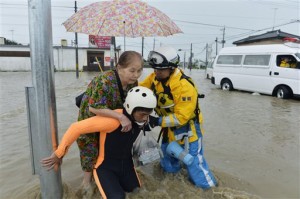 Police officers help a woman to evacuate through a flooded street in Joso, Ibaraki prefecture, northeast of Tokyo Thursday, Sept. 10, 2015. Heavy rains batter Japan for the second day, causing flooding and landslides in eastern Japan. (Kyodo News via AP) JAPAN OUT, MANDATORY CREDIT 