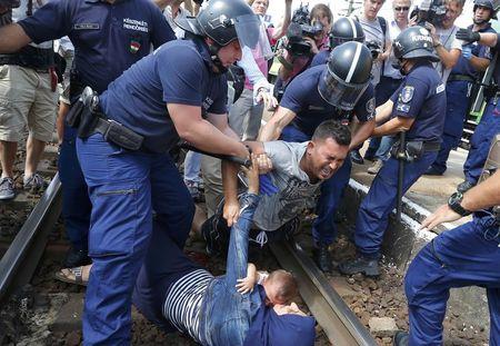 Hungarian policemen detain migrants on the tracks as they wanted to run away at the railway station in the town of Bicske, Hungary, camp for refugees and asylum seekers is located in Bicske. REUTERS/Laszlo Balogh