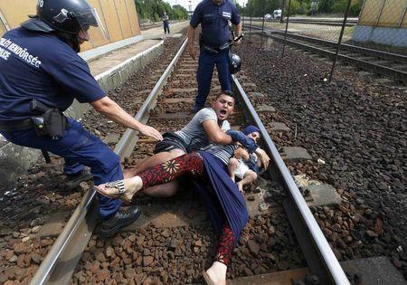 Hungarian policemen stand by the family of migrants as they wanted to run away at the railway station in the town of Bicske, Hungary, September 3, 2015. REUTERS/Laszlo Balogh